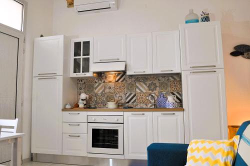 a kitchen with white cabinets and a stove at Casa Teresa in Portoscuso