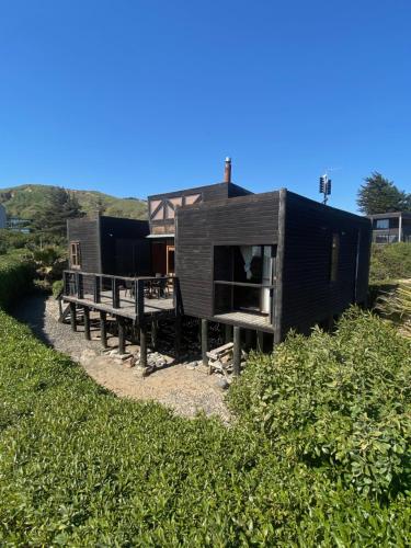 a black tiny house sitting on top of a field at Matanzas Casita Playa in Navidad