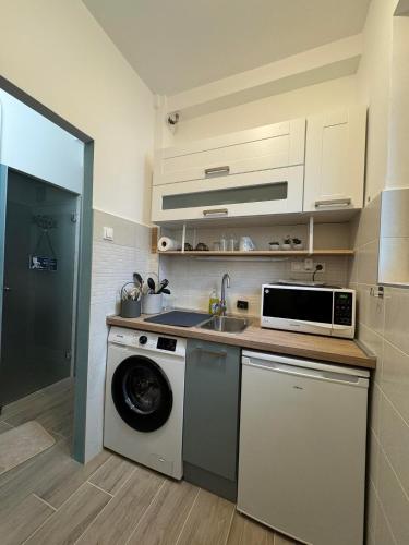 a kitchen with a washing machine and a sink at Szeged Sunshine Apartman in Szeged