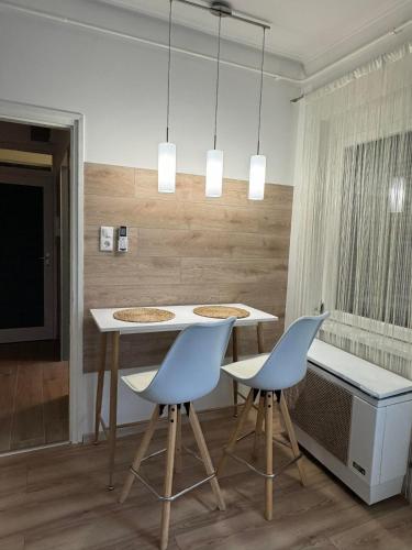 a kitchen with a table and two blue chairs at Szeged Sunshine Apartman in Szeged