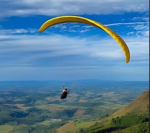 a paraglider is flying in the sky over a field at Residencial GO 305 - in Poços de Caldas