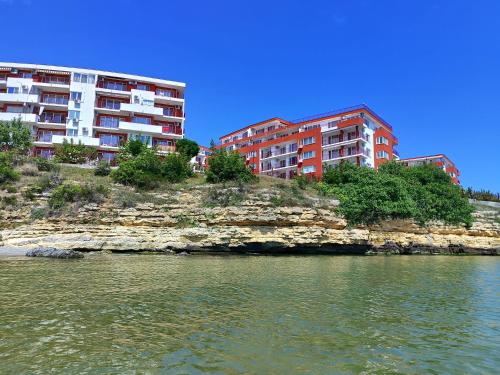 two buildings on a hill next to a body of water at Aria private apartments in Fort Noks Grand Resort - Saint Vlas in Elenite