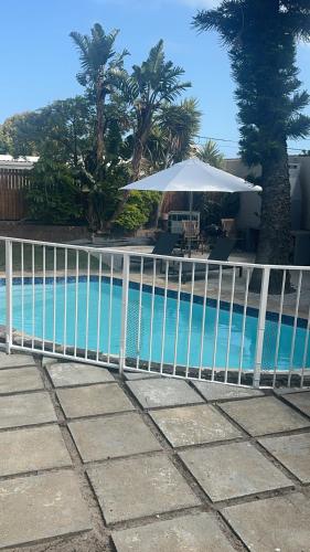 a white fence next to a swimming pool at Tranquil Pool View in Cape Town