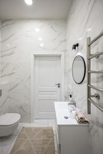 a white bathroom with a toilet and a sink at Vilnius Old-Town Renaissance Studios in Vilnius