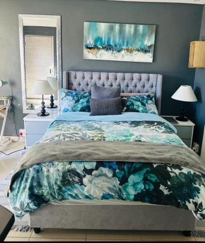 a bedroom with a bed with a floral bedspread at Tranquil Pool View in Cape Town