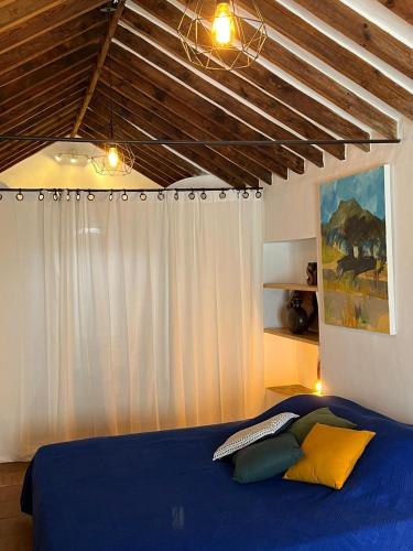 a bedroom with a blue bed and a white curtain at Bed&Breakfast Al Campanario in Cómpeta