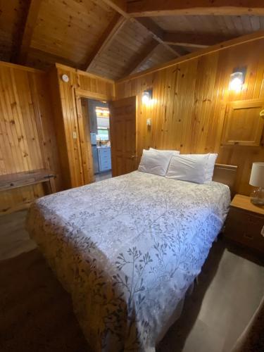 a bedroom with a large bed with wooden walls at Adventures East Cottages and Campground in Baddeck Inlet