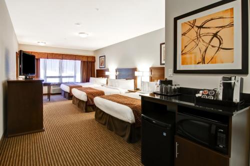 a hotel room with two beds and a television at Canalta Hotel Melfort in Melfort