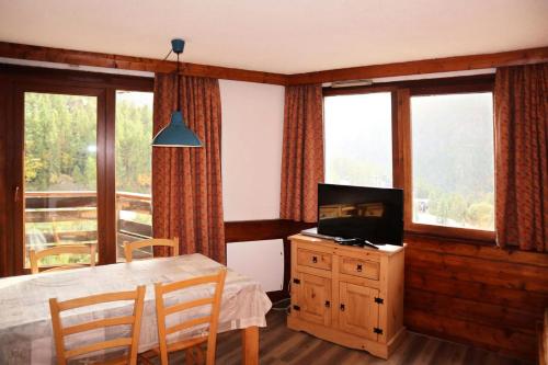 d'une salle à manger avec une table, une télévision et des fenêtres. dans l'établissement Résidence Le Belvedere - APPARTEMENT N° 706 LE BELVEDERE MAE-4054, aux Orres