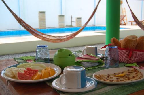 een tafel met een ontbijt van fruit en een hangmat bij Pousada Janela da Cor in Jericoacoara