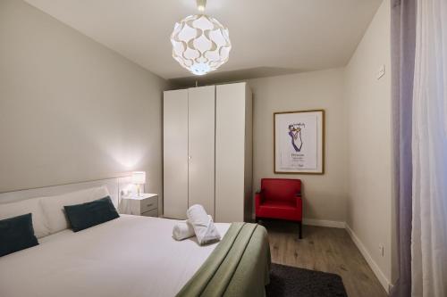 a bedroom with a white bed and a red chair at Mercaderes 9 by Clabao in Pamplona