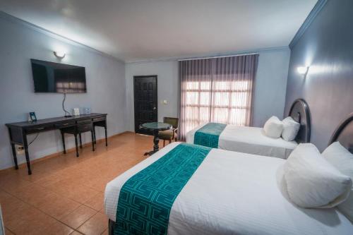 a hotel room with two beds and a desk at InHouse Select Hacienda Tres Rios Hotel Culiacán in Culiacán