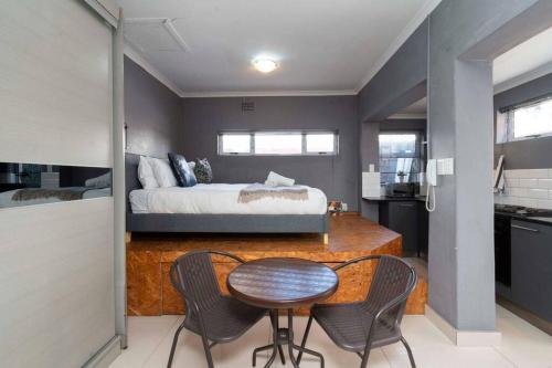 a bedroom with a bed and a table and chairs at Simple Studio in Sea Point in Cape Town
