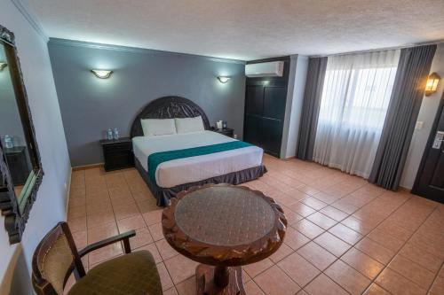 a hotel room with a bed and a table and chairs at InHouse Select Hacienda Tres Rios Hotel Culiacán in Culiacán