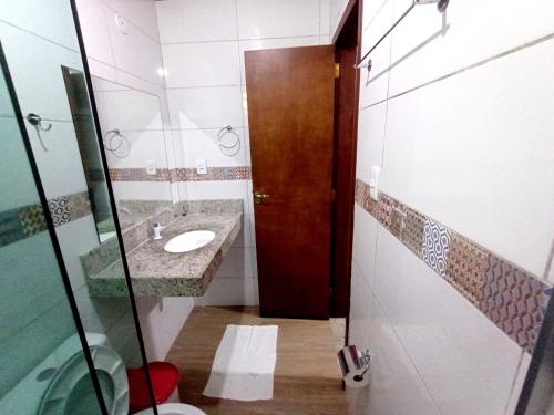 a bathroom with a sink and a wooden door at Pousada Lagoa Flat in Morro de São Paulo