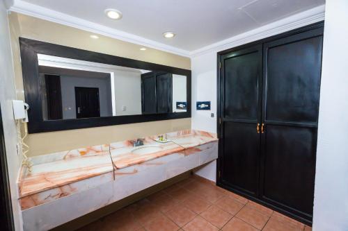 a bathroom with a large mirror and black cabinets at InHouse Select Hacienda Tres Rios Hotel Culiacán in Culiacán