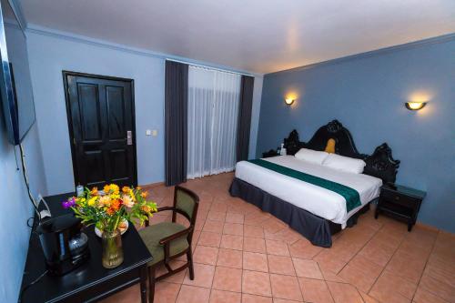 a bedroom with a bed and a table with flowers at InHouse Select Hacienda Tres Rios Hotel Culiacán in Culiacán