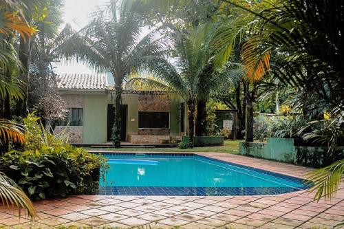 a swimming pool in front of a house with palm trees at Pousada Casa Mendes in Guapimirim