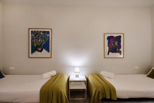 two beds in a room with a table and pictures at Mercaderes 9 by Clabao in Pamplona