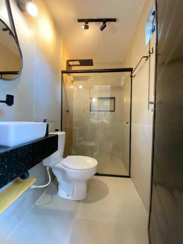 a bathroom with a toilet and a glass shower at LOFT Mar 101 - Com Piscina Privativa a Poucos Passos de Vilas Gastronômicas Polo de Artesanato e Associação Peixe-boi in Pôrto de Pedras