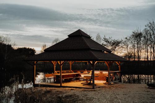 a wooden gazebo with a table and chairs at Dom Parlinek agroturtstyka wędkowanie sauna jacuzzi in Dąbrowa