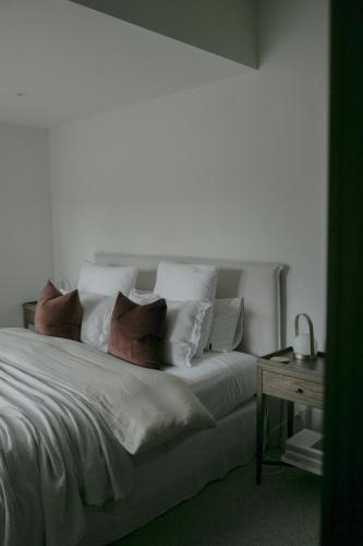 a bedroom with a white bed with pillows and a table at Sister's Sanctuary in Raglan