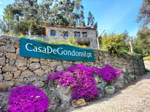 a sign on a stone wall with purple flowers at Casa de Gondomil in Alpendurada