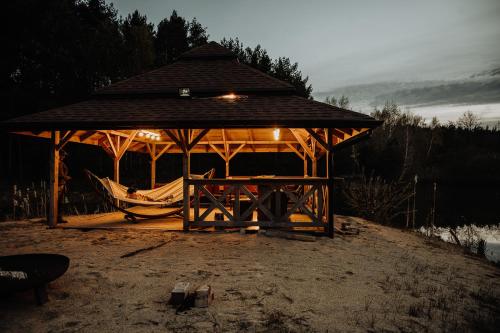 a wooden gazebo with a table and a hammock at Dom Parlinek agroturtstyka wędkowanie sauna jacuzzi in Dąbrowa