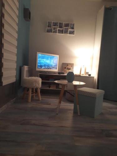 Il comprend un salon doté d'une télévision et d'une table avec une chaise. dans l'établissement Au bord des Dunes, à Camiers