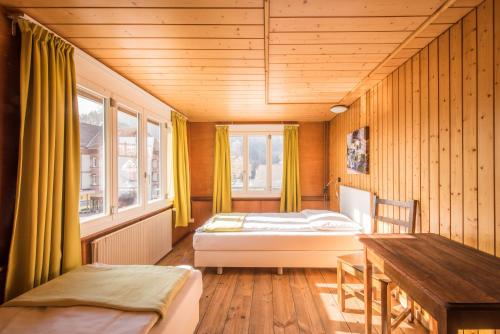 una camera con 2 letti, una scrivania e finestre di Hotel Tell and Apartments a Interlaken