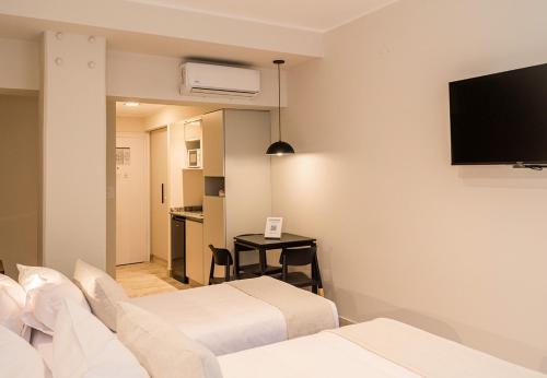 a hotel room with two beds and a flat screen tv at RentUp Suites Salta in Salta