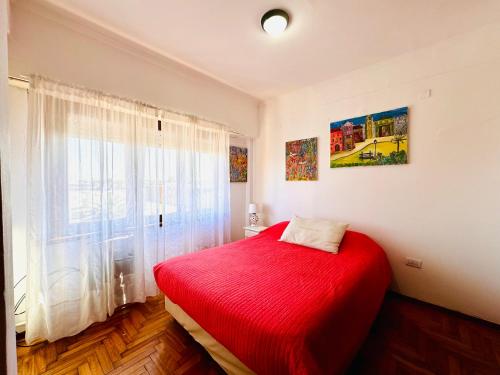 a bedroom with a red bed and a window at Departamento A Mar in Mar del Plata