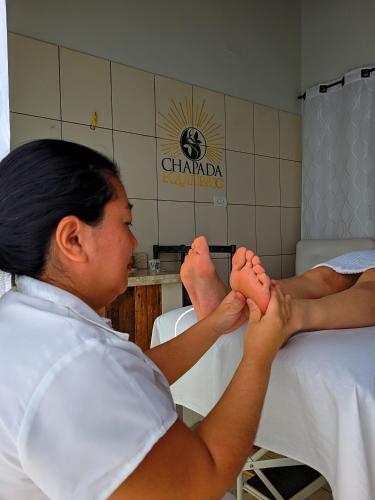 a woman sitting on a bed with her feet at Pousada Chapada Equilibrio in Chapada dos Guimarães