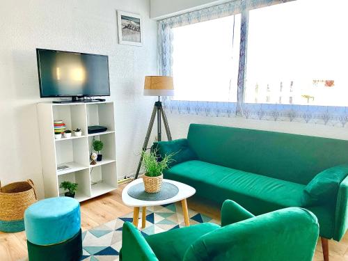 een woonkamer met een groene bank en een tv bij Caporizon-Cap239-Vue mer-50m plage in Marillac