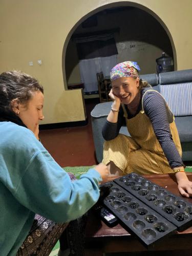 a woman shaking hands with a woman sitting at a table at Bonnie's Homestay in Gasanze