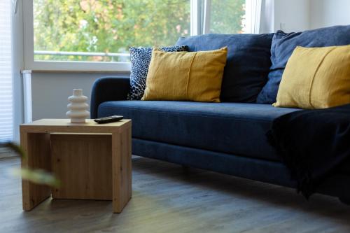 a blue couch with yellow pillows and a wooden table at BEST STAY CityAppartment Hünfeld- SmartTV FreeWlan Balkon, in wenigen Minuten am Bahnhof, Innenstadt und doch ruhig gelegen - ideal für Paare oder Geschäftsreisen in Hünfeld