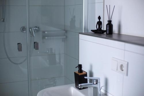a bathroom with a sink and a glass shower at BEST STAY CityAppartment Hünfeld- SmartTV FreeWlan Balkon, in wenigen Minuten am Bahnhof, Innenstadt und doch ruhig gelegen - ideal für Paare oder Geschäftsreisen in Hünfeld