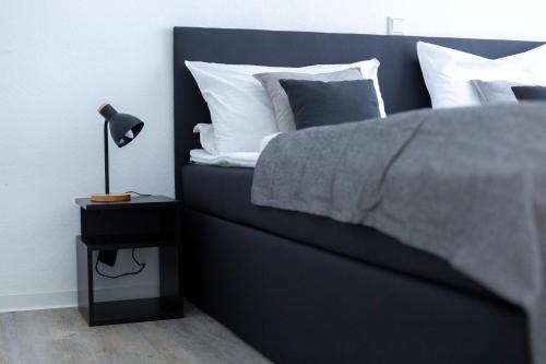 a bedroom with a bed and a night stand with a lamp at BEST STAY CityAppartment Hünfeld- SmartTV FreeWlan Balkon, in wenigen Minuten am Bahnhof, Innenstadt und doch ruhig gelegen - ideal für Paare oder Geschäftsreisen in Hünfeld