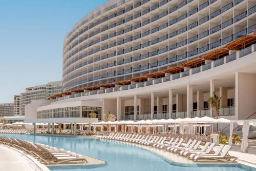 a hotel with a swimming pool and chairs and a building at AVA Resort Cancun - All Inclusive in Cancún