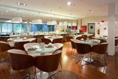 a restaurant with tables and chairs and a kitchen at Porto Trindade Hotel in Porto