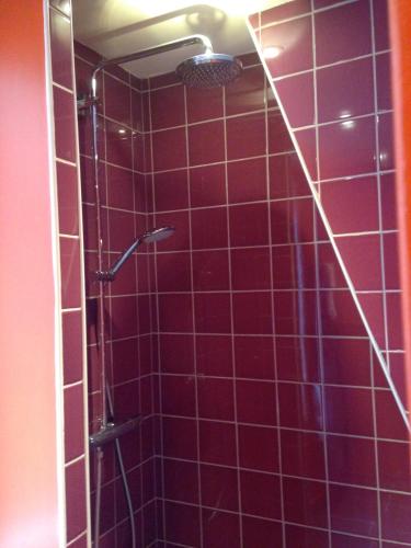 - une douche carrelée de rouge avec un pommeau de douche dans l'établissement Côté Saint-Léonard - Honfleur, à Honfleur