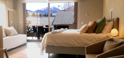 a bedroom with a bed and a couch and a balcony at Blizu in Villa La Angostura