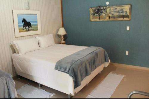 a bedroom with a bed with a horse painting on the wall at Pousada Casa Mendes in Guapimirim