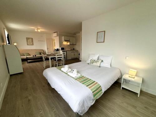 een slaapkamer met een groot wit bed en een keuken bij L'Océane, studio spacieux avec place de parking, Proche plage in La Palud