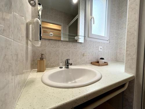 een badkamer met een witte wastafel en een spiegel bij L'Océane, studio spacieux avec place de parking, Proche plage in La Palud