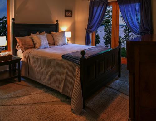 a bedroom with a large bed with blue curtains at The Lakehouse of Braeloch in Colchester