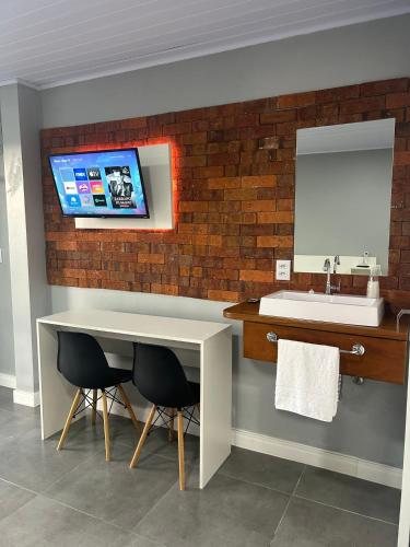 a bathroom with a sink and a table and a mirror at Vista da Serra. in Gramado