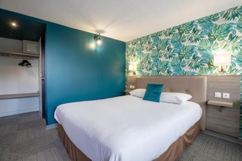 a large bed in a room with a blue wall at Kyriad Direct Laon in Laon
