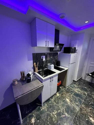 une cuisine avec un évier et des lumières violettes. dans l'établissement Lovers' Studio, à Bagnolet