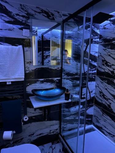 La salle de bains est pourvue d'un lavabo bleu et d'un homme dans le miroir. dans l'établissement Lovers' Studio, à Bagnolet